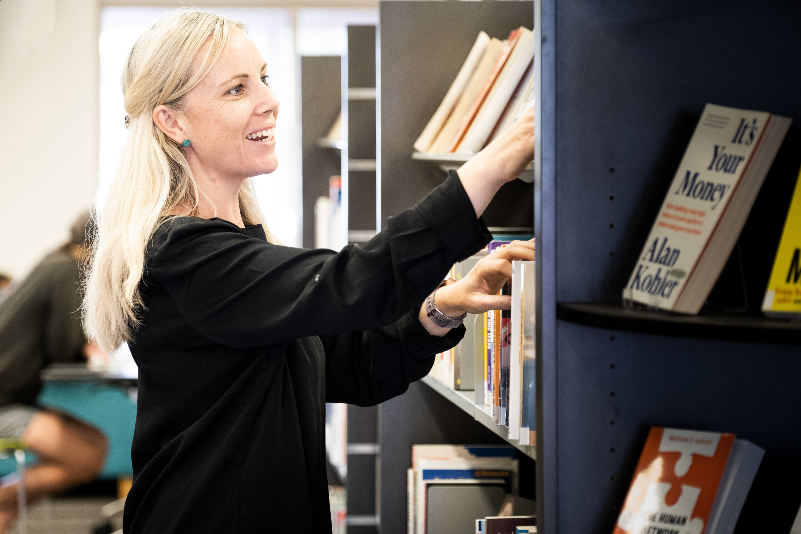 A woman sorting books on the shelves in the library.