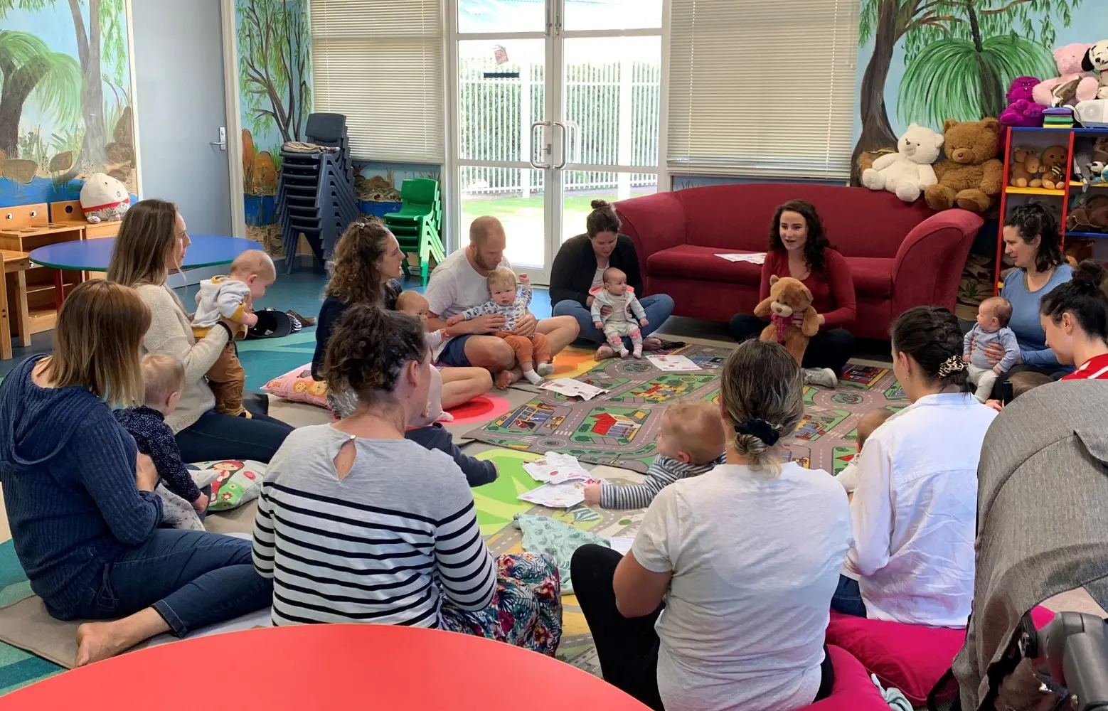 A group of adults sitting in a circle, each holding babies.