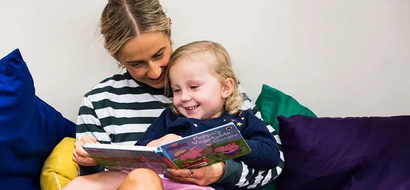 A woman reading a book to a child.