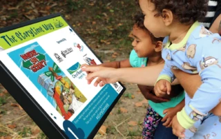 Toddler pointing at a sign with a story on it.