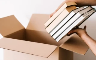 Books being placed into a cardboard box.