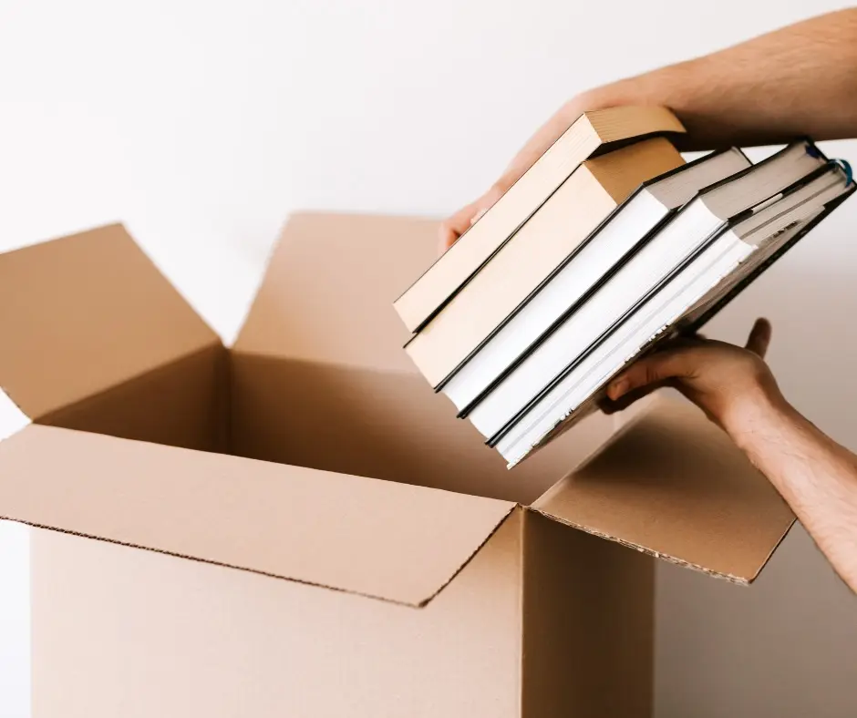 Books being placed into a cardboard box.