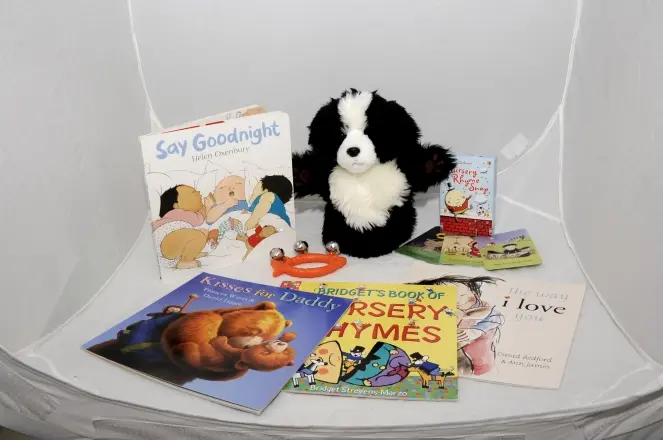 Busselton-Libraries-Discovery-Backpacks An arrangement of four books, cards for a game of snap, a puppet, and a baby's bell toy.