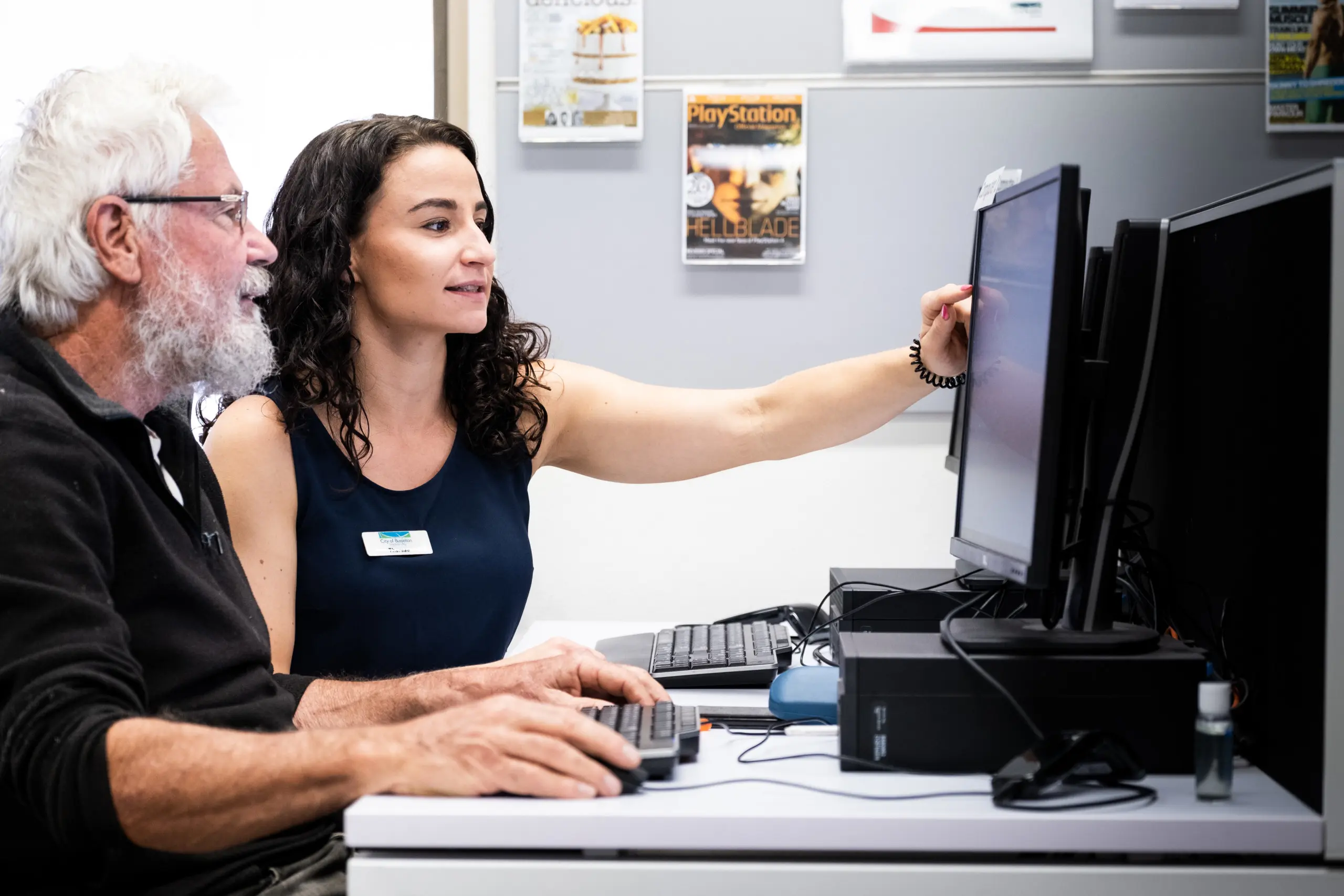 A woman assisting an older man with using a computer.