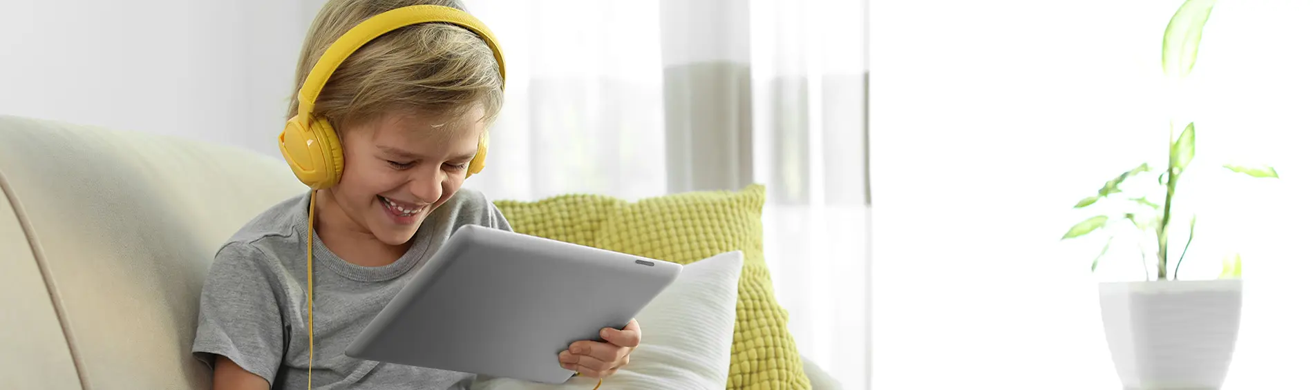 A child wearing headphones and looking at a tablet.