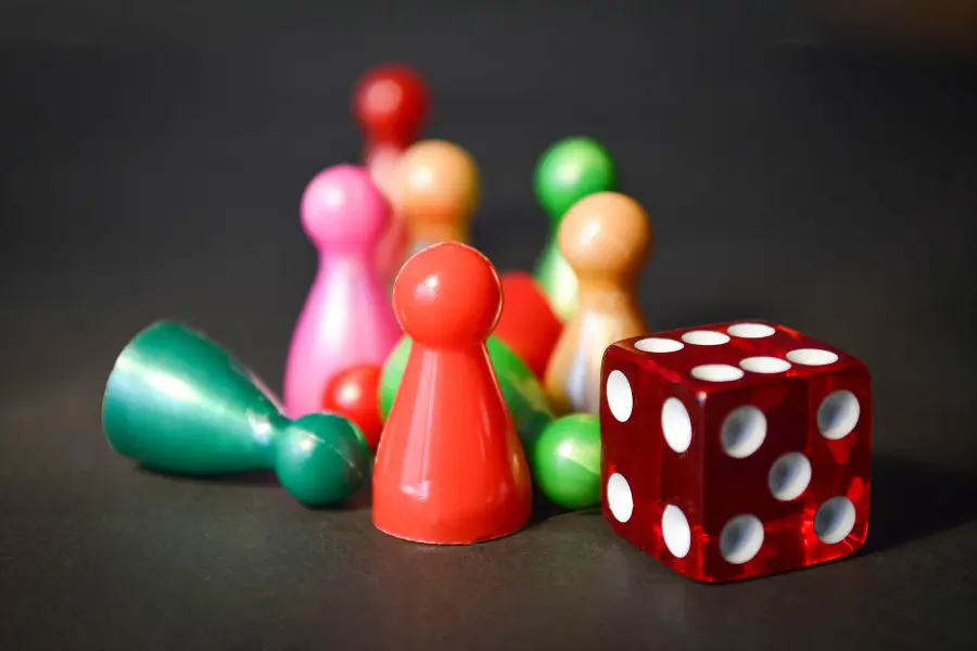 A selection of multicoloured pawns and a die.