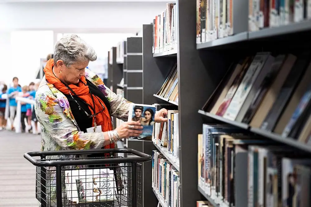 A woman putting books back onto library shelves.