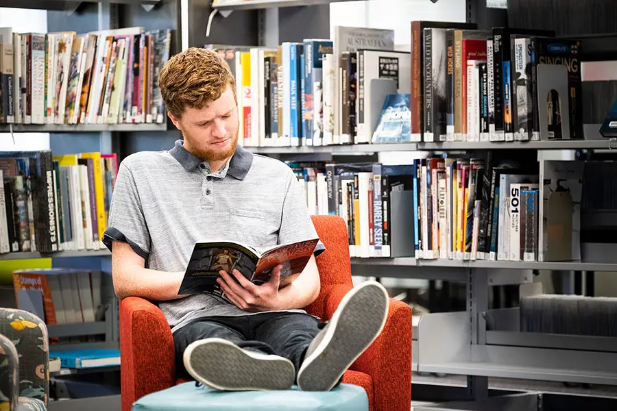A man reading a book in a library.