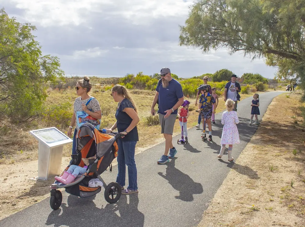 A group of people walking along The Storytime Way, stopping at the next plinth.