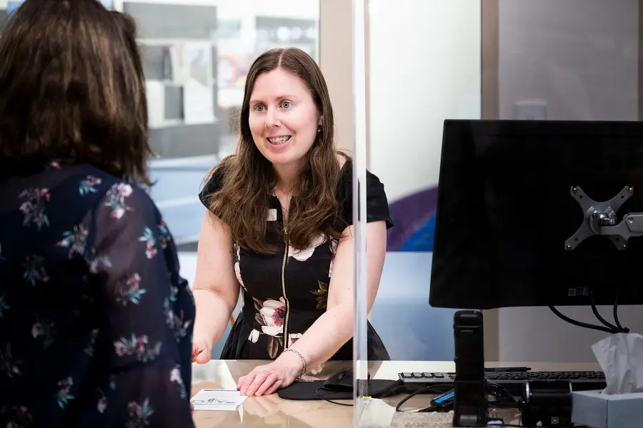 A librarian explaining a flier to a library patron.