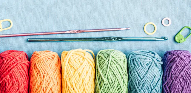 An image of coloured yarn laid in a row across a blue tabletop.