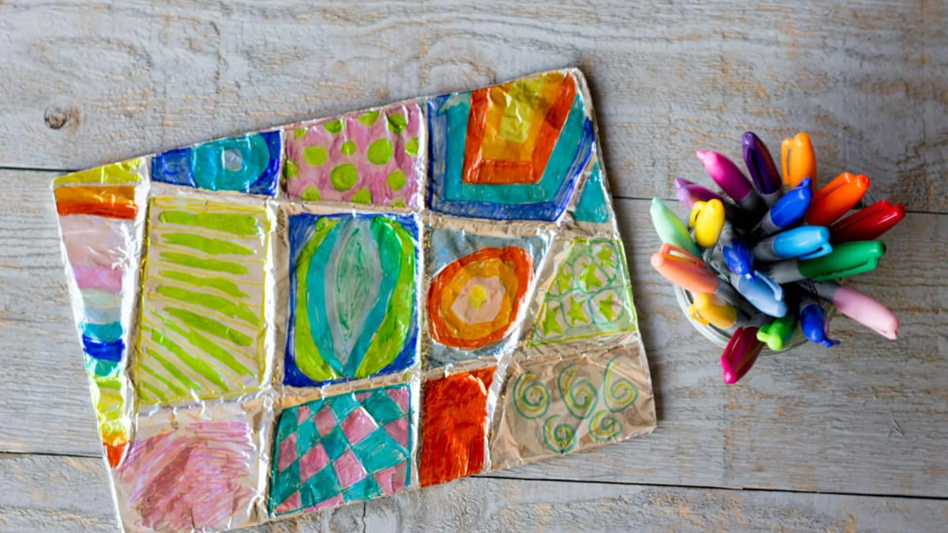 An image of children's artwork made from aluminium foil and paint.